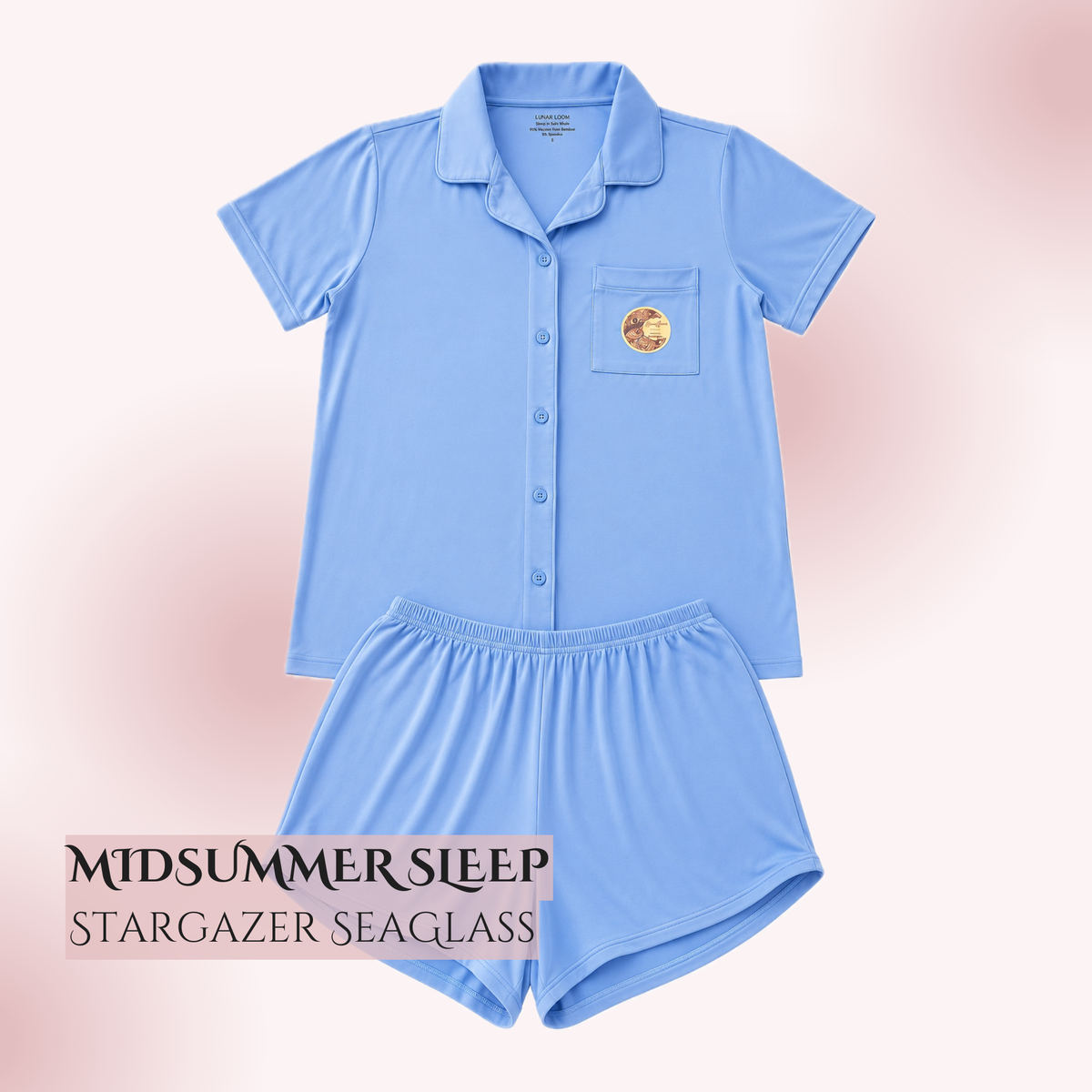 A sensory safe bamboo pajamas for sensitive neurodivergent individuals, light blue two-piece pajama set consisting of a short-sleeve button-front collared top and matching shorts, shown on a soft pink gradient background. A small circular patch is visible on the chest pocket, and text at the bottom reads 'MIDSUMMER SLEEP' and 'STARGAZER SEAGlass'.